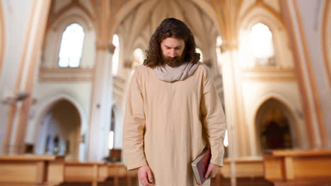 Portrait-Of-Man-Wearing-Robes-With-Long-Hair-And-Beard-Representing-Figure-Of-Jesus-Christ-Holding-Bible-In-Church
